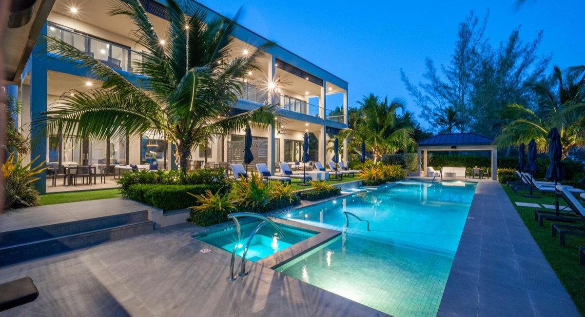 Pool and hot tub at dusk at the Haven Pool, Black Urchin Resort, Grand Cayman, with lit villa terraces and palm trees